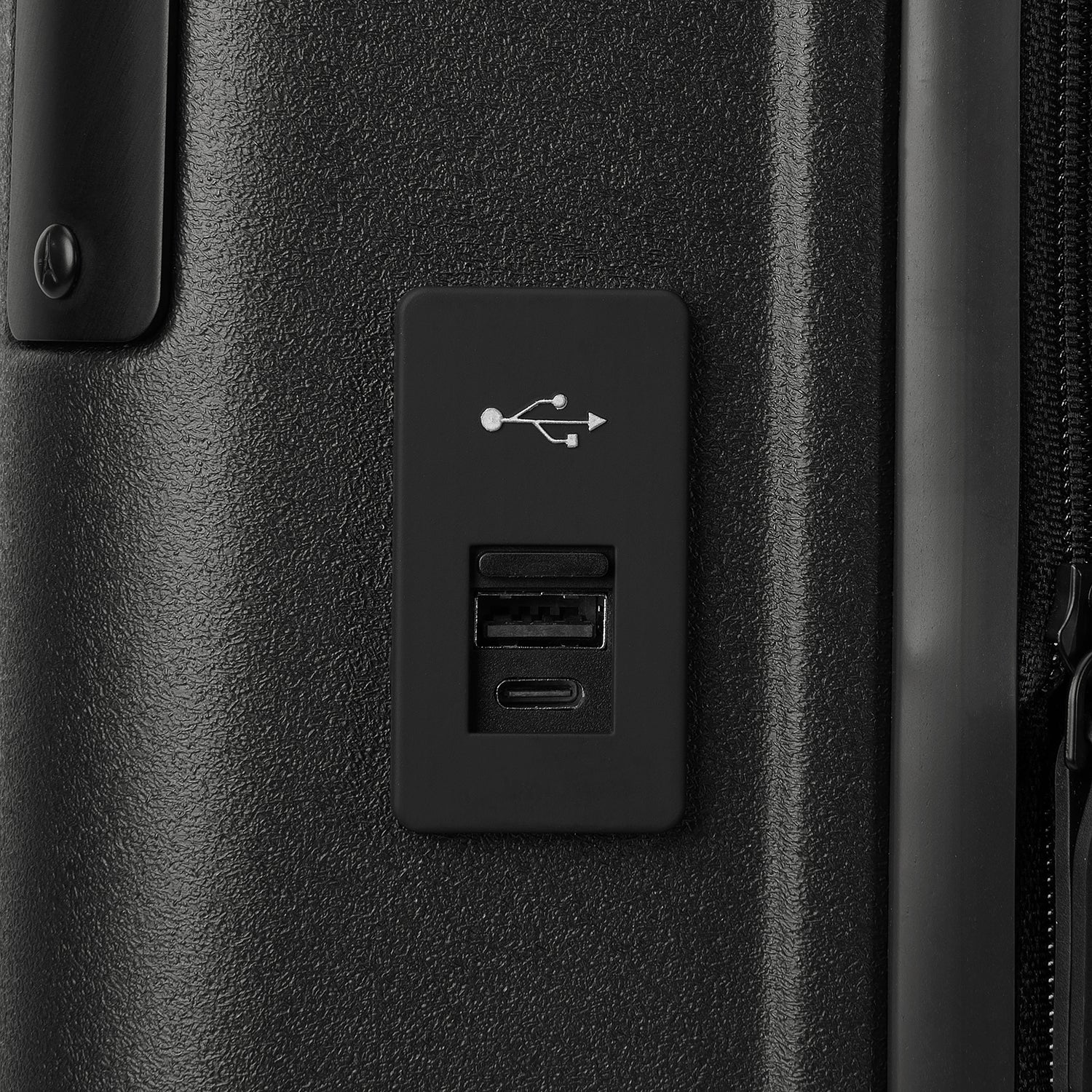 Macro detail view of the external USB-A and USB-C charging ports on the Travelpro Platinum Elite Compact Carry-On Hardside Spinner in Shadow Black, highlighting the integrated power connectivity.