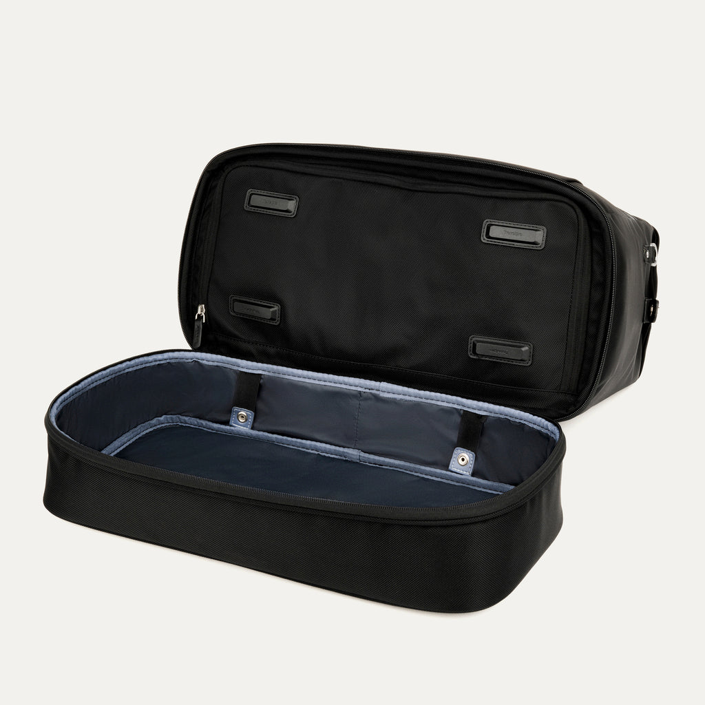 interior view of the open drop-bottom compartment on the black travelpro platinum elite weekender bag, showing the spacious empty section with a grey lining and internal snap-button compression straps.