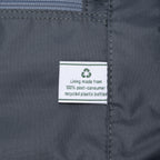 a close-up of the interior lining of the true navy travelpro platinum elite weekender bag, showing a white fabric label that reads "lining made from 100% post-consumer recycled plastic bottles" with a green recycling symbol.
