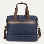 front view of the true navy travelpro platinum elite drop-bottom weekender bag, featuring its signature two-compartment design with premium brown leather trim, chrome zippers, and a removable shoulder strap.