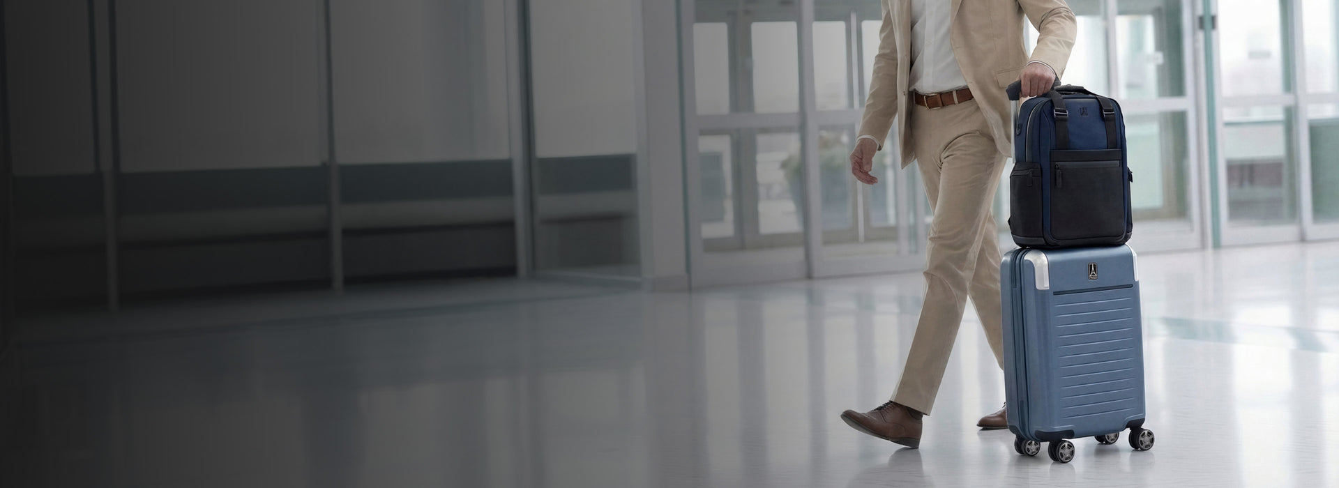desktop lifestyle banner of a traveler with the travelpro® platinum® elite hardside carry-on in dark sky blue and the platinum® elite altitude medium expandable backpack in aviator navy, illustrating the stacking capability for easy transit.