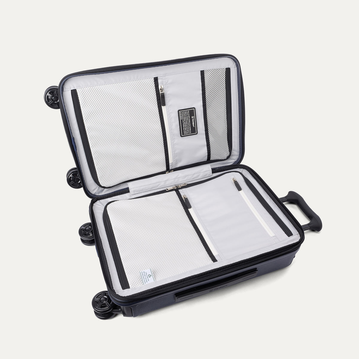 Interior packing view of the Travelpro Platinum Elite Carry-On Hardside Spinner in Aviator Navy, featuring dual zippered divider panels and the ECOFAB™ lining made from 100% recycled plastic bottles.