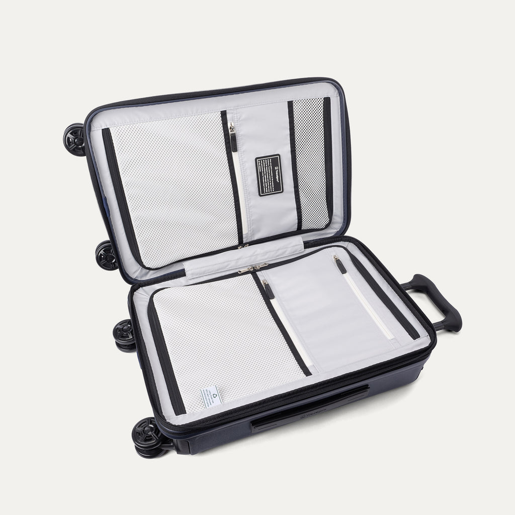 Interior packing view of the Travelpro Platinum Elite Carry-On Hardside Spinner in Aviator Navy, featuring dual zippered divider panels and adjustable hold-down straps for organized travel.
