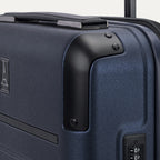 Close-up detail of the Travelpro Platinum Elite Carry-On Hardside Spinner in Aviator Navy, showing the protective corner armor and the integrated TSA-approved combination lock on the textured hardshell.