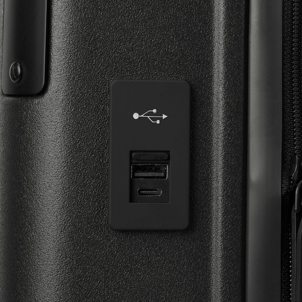 Macro detail view of the external USB-A and USB-C charging ports on the Travelpro Platinum Elite Carry-On Hardside Spinner in Jet Black, highlighting the integrated power connectivity for mobile devices.