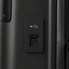 Macro detail view of the external USB-A and USB-C charging ports on the Travelpro Platinum Elite Carry-On Hardside Spinner in Jet Black, highlighting the integrated power connectivity for mobile devices.