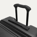 Close-up of the Travelpro Platinum Elite Large Check-In Hardside Spinner in Jet Black, featuring the sturdy PowerScope Lite handle with a comfortable, rubberized Contour Grip.