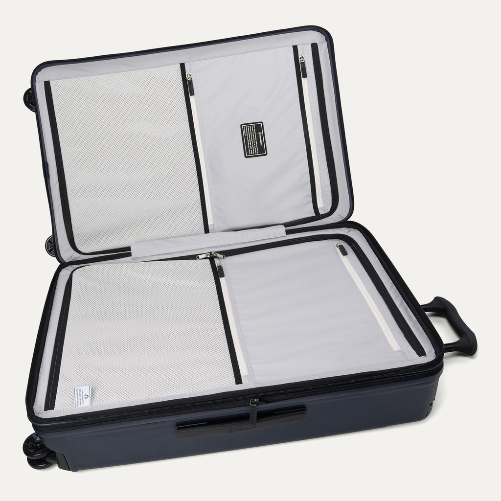 Interior view of the open Travelpro Platinum Elite large Check-In Hardside Spinner in Aviator Navy, featuring dual zippered divider panels, ECOFAB recycled lining, and spacious dual packing compartments.