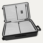 Interior packing view of the Travelpro Platinum Elite Large Check-In Hardside Spinner in Jet Black, featuring dual zippered divider panels, multiple accessory pockets, and a water-resistant compartment.