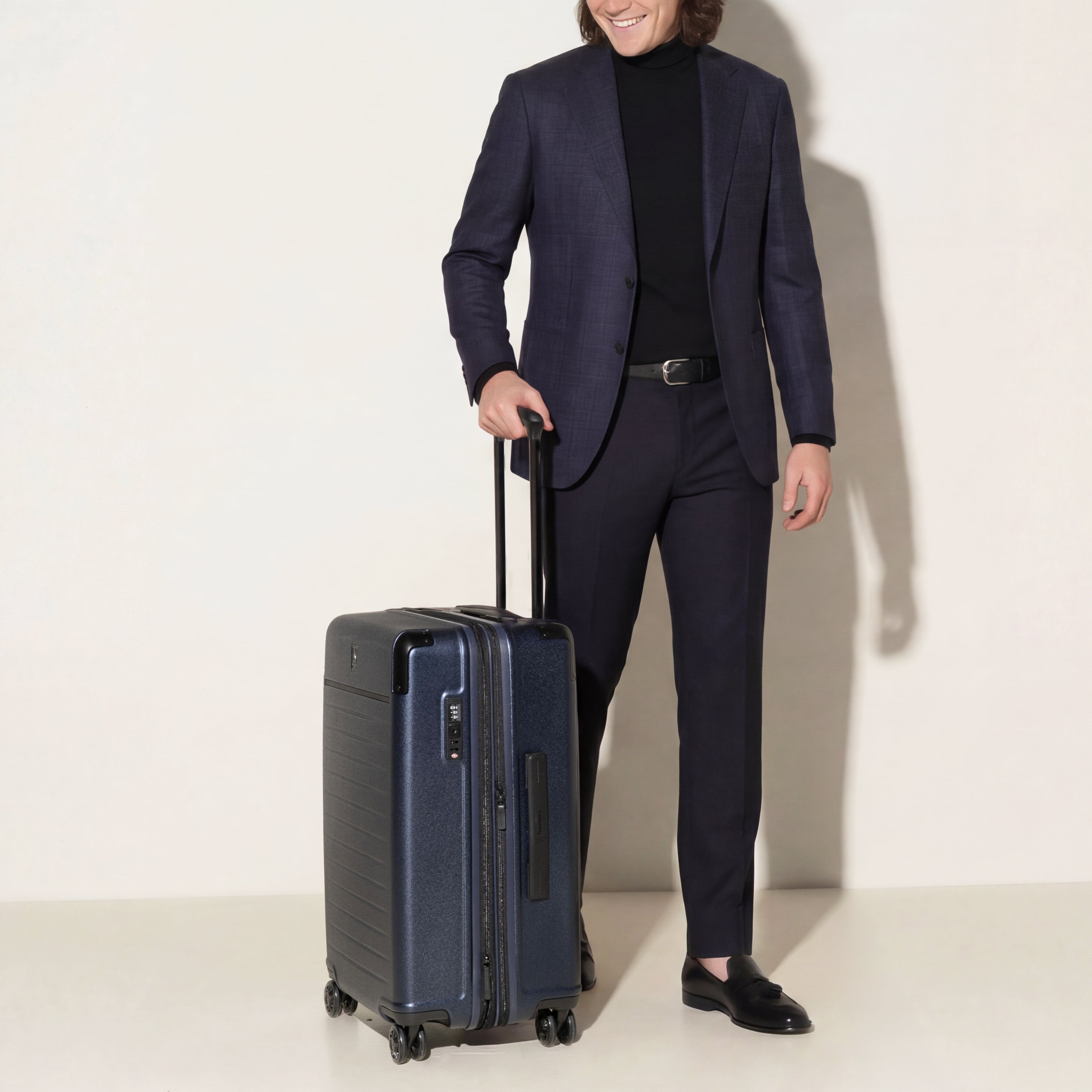 Front view of the Travelpro Platinum Elite Medium Check-In Hardside Spinner in Aviator Navy, featuring a durable polycarbonate shell, polished aluminum corner armor, and genuine leather trim.