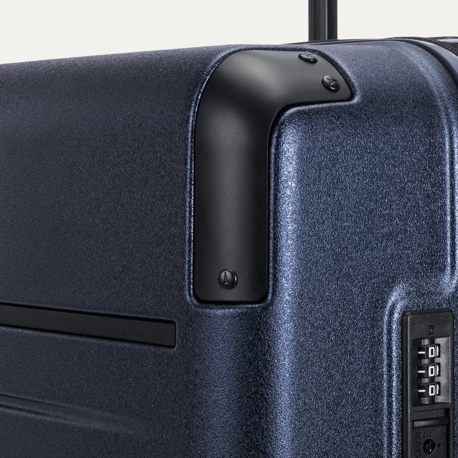 Close-up detail of the Travelpro Platinum Elite Medium Check-In Hardside Spinner in Aviator Navy, showing the protective polished aluminum corner armor and the integrated TSA-approved combination lock.