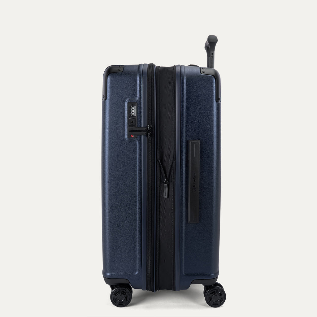 Side profile view of the Travelpro Platinum Elite Medium Check-In Hardside Spinner in Aviator Navy, showing the zippered expansion feature that provides 2 inches of additional packing capacity.