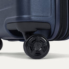 Close-up of the dual spinner wheels on the Travelpro Platinum Elite Medium Check-In Hardside Spinner in Aviator Navy, featuring the self-aligning MagnaTrac® technology and polished silver-tone wheel hubs.