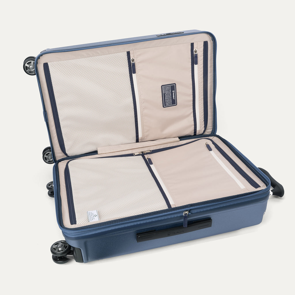Interior packing view of the Travelpro Platinum Elite Medium Check-In Hardside Spinner in Dark Sky Blue, featuring dual zippered divider panels and the ECOFAB™ lining made from 100% recycled plastic bottles.
