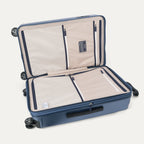 Interior packing view of the Travelpro Platinum Elite Medium Check-In Hardside Spinner in Dark Sky Blue, featuring dual zippered divider panels and the ECOFAB™ lining made from 100% recycled plastic bottles.