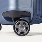 Close-up of the dual spinner wheels on the Travelpro Platinum Elite Medium Check-In Hardside Spinner in Dark Sky Blue, featuring the self-aligning MagnaTrac® technology and polished silver-tone wheel hubs.