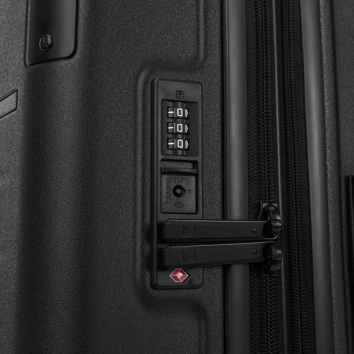 Close-up detail of the Travelpro Platinum Elite Medium Check-In Hardside Spinner in Jet Black, showing the integrated TSA-approved combination lock and secure zipper pulls on the polycarbonate shell.