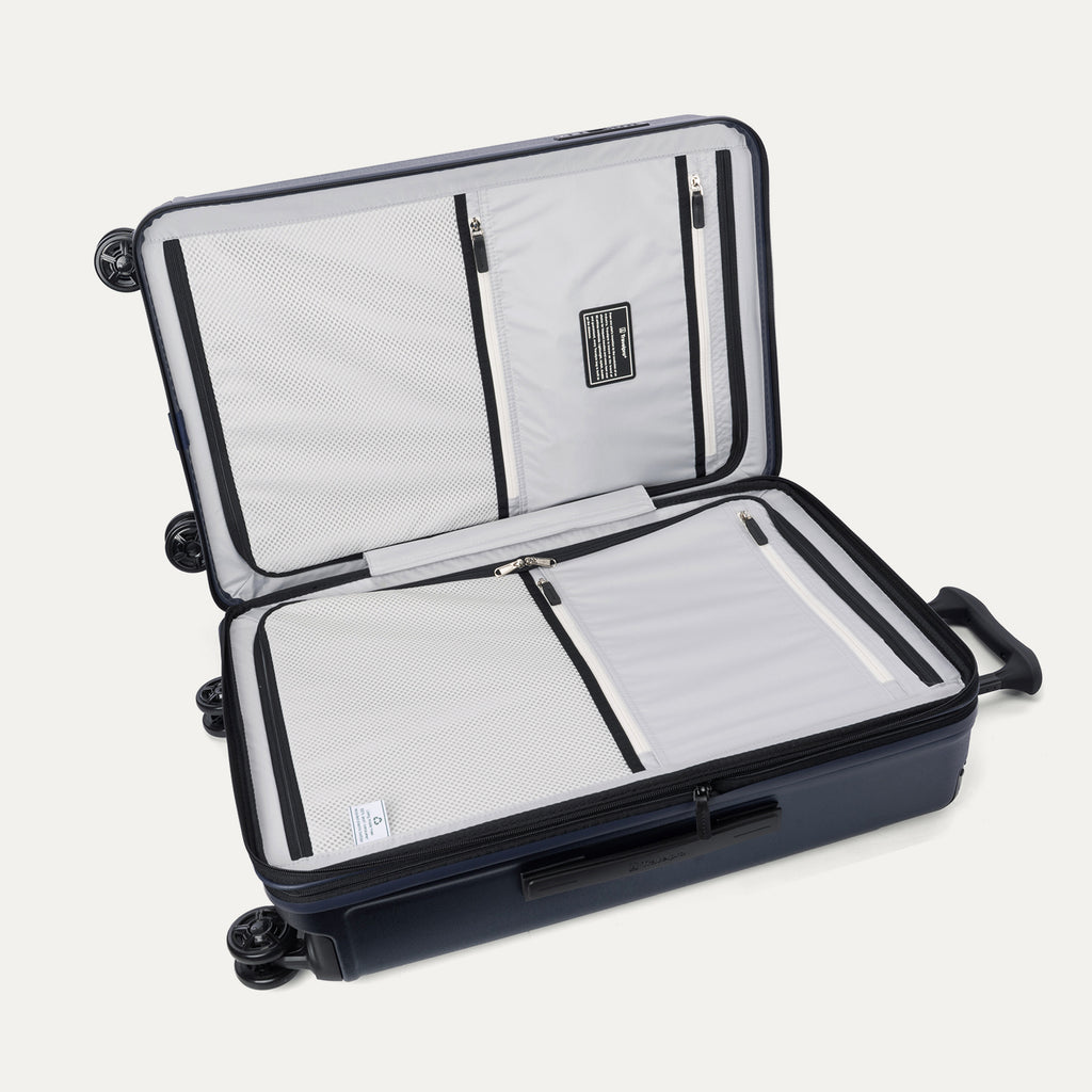 Interior packing view of the Travelpro Platinum Elite Medium Check-In Hardside Spinner in Aviator Navy, featuring dual zippered divider panels, multiple accessory pockets, and a water-resistant pocket.