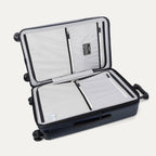 Interior packing view of the Travelpro Platinum Elite Medium Check-In Hardside Spinner in Aviator Navy, featuring dual zippered divider panels, multiple accessory pockets, and a water-resistant compartment.