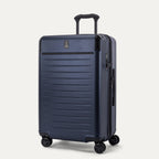 Front 3/4 view of the Travelpro Platinum Elite Medium Check-In Hardside Spinner in Aviator Navy, featuring a scuff-resistant polycarbonate shell, aluminum corner armor, and 360-degree spinner wheels.