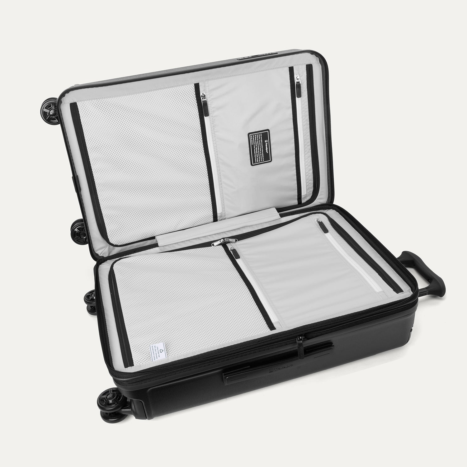 Interior packing view of the Travelpro Platinum Elite Medium Check-In Hardside Spinner in Jet Black, featuring dual zippered divider panels, multiple accessory pockets, and a water-resistant compartment.