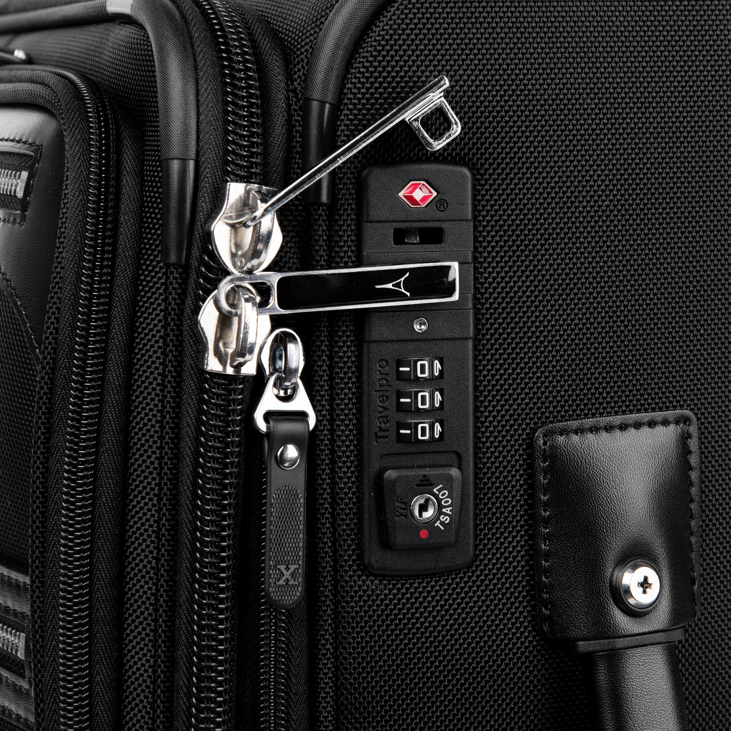close-up view of the integrated tsa-compliant combination lock on the shadow black travelpro platinum® elite international carry-on spinner, showing two chrome zipper pulls secured in the locking mechanism and a leather side handle detail.