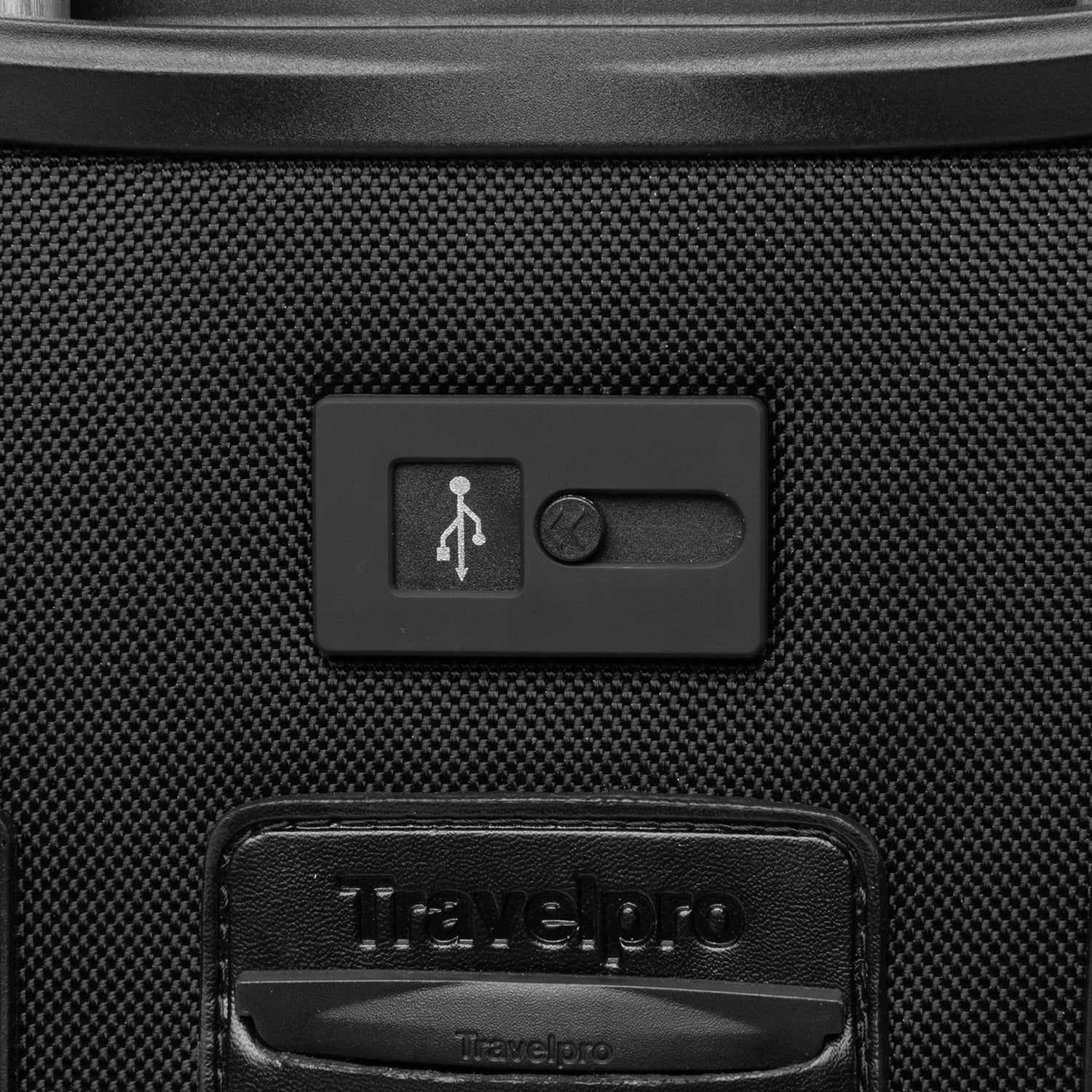 extreme close-up view of the external usb port on the shadow black travelpro platinum® elite international carry-on spinner, showing the sliding port cover and the embossed travelpro logo on the surrounding fabric.