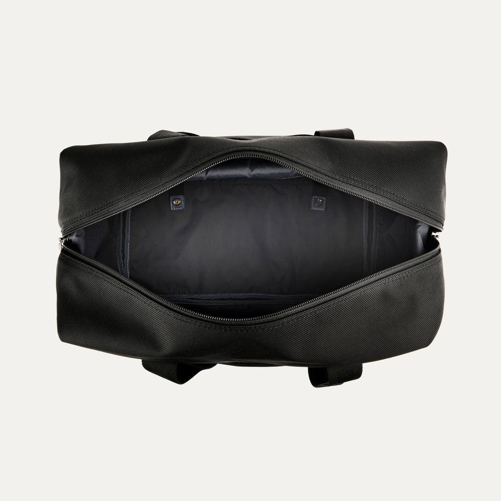 top-down view of the open shadow black travelpro platinum elite drop-bottom weekender bag, showing the spacious empty main compartment with a dark grey lining and interior zippered accessory pockets.