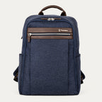 front hero view of the true navy travelpro platinum® elite slim laptop backpack 16l, featuring a textured navy blue fabric exterior with premium dark brown leather accents on the top handle and front zipper trim.