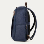 side profile view of the true navy travelpro platinum® elite slim laptop backpack 16l, showing its thin design, textured navy fabric, and dark brown leather accents on the top handle and zipper pulls.