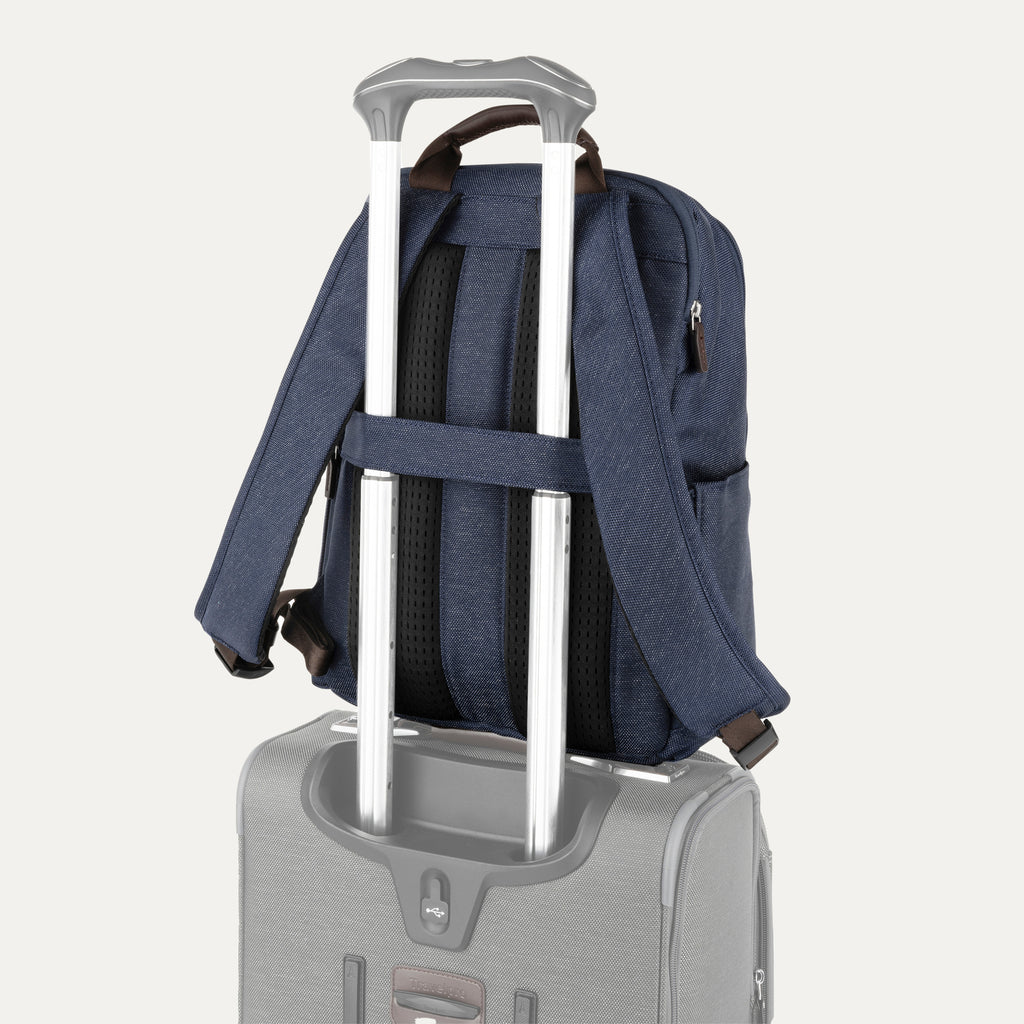 rear view of the true navy travelpro platinum® elite slim laptop backpack 16l stacked on a grey rolling suitcase, showing the integrated trolley strap with dark brown leather accents secured over the extension handle.