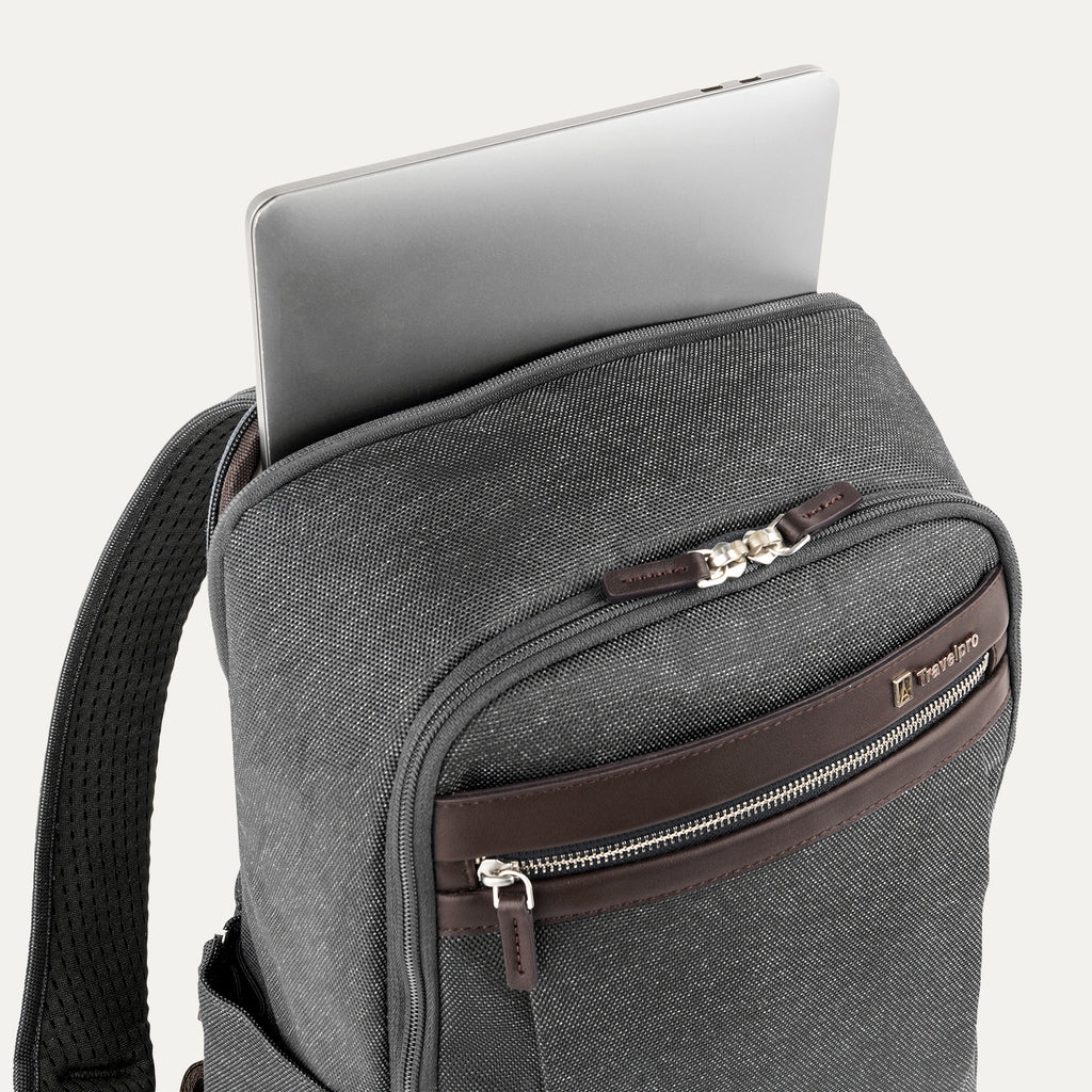 close-up view of the vintage grey travelpro platinum® elite slim laptop backpack 16l, showing a silver laptop being inserted into the padded rear electronics compartment with dark brown leather trim.