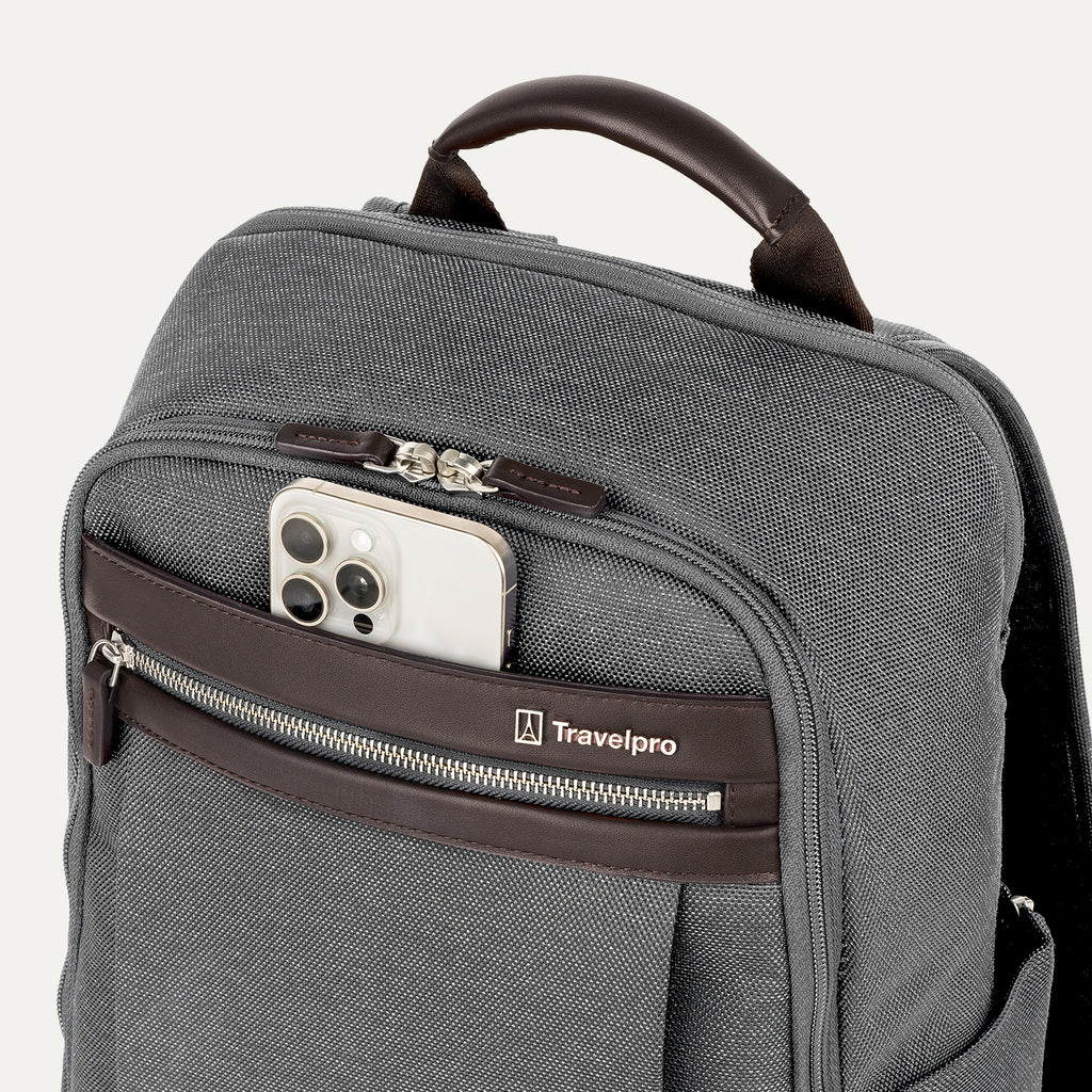 close-up view of the vintage grey travelpro platinum® elite slim laptop backpack 16l, showing a white smartphone being tucked into the magnetic quickslip front pocket with dark brown leather trim.