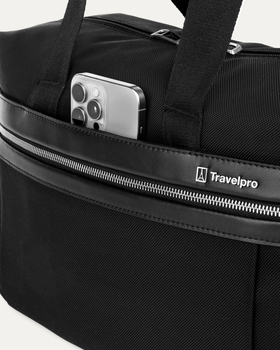 close-up of the front exterior of the black travelpro platinum elite underseat tote, showing a smartphone tucked into the quickslip pocket with matching black leather trim and the travelpro logo.