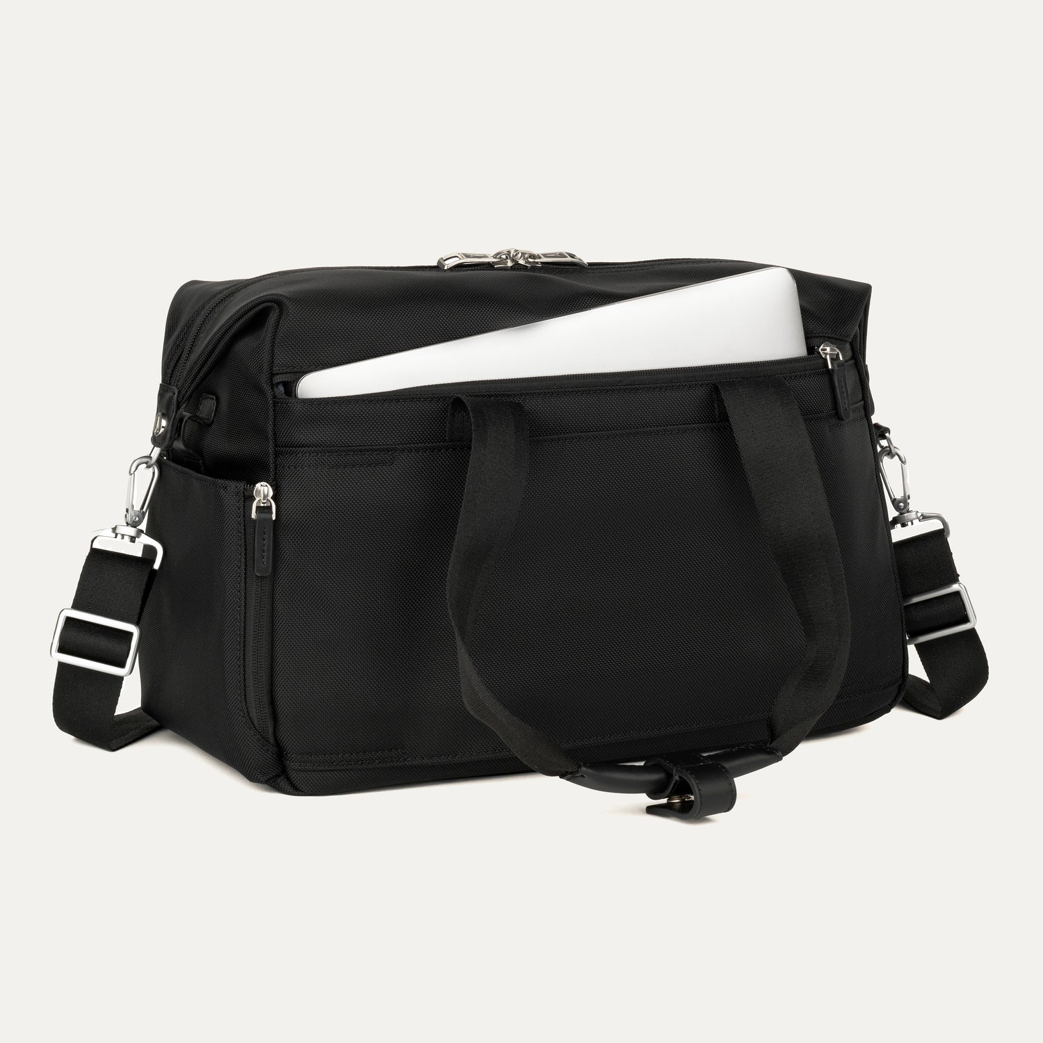 a black travelpro platinum elite underseat tote shown with a white laptop being inserted into the internal padded electronics sleeve, highlighting the bag's organization and protection for tech devices.