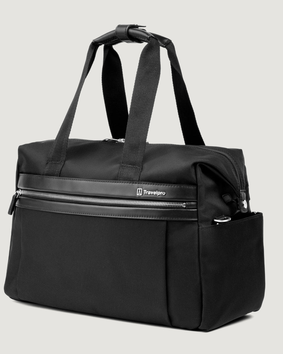 a three-quarter perspective view of the black travelpro platinum elite underseat tote, highlighting the textured black fabric, matching black leather trim, front zippered pocket, and side accessory pocket.