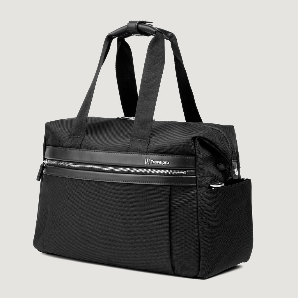 a three-quarter perspective view of the black travelpro platinum elite underseat tote, highlighting the textured black fabric, matching black leather trim, front zippered pocket, and side accessory pocket.