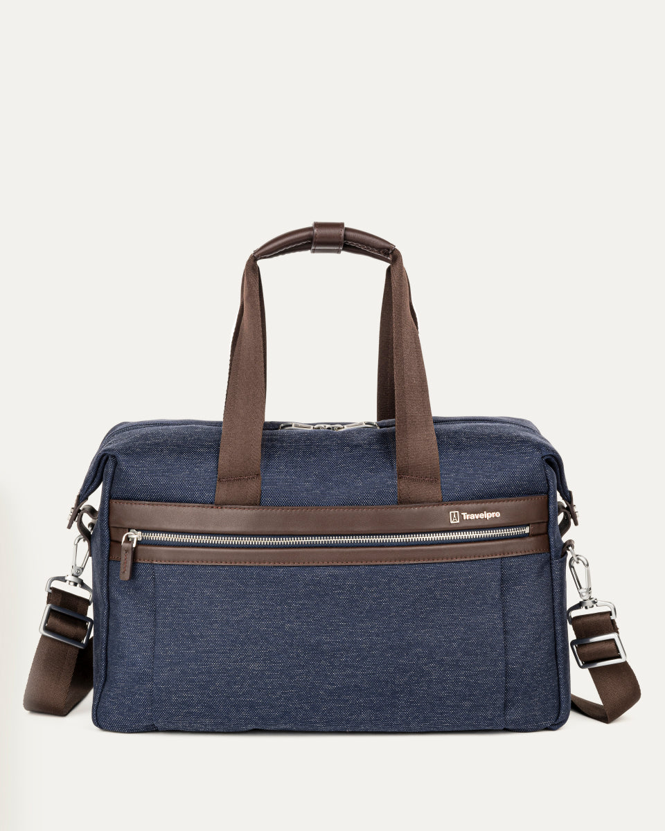 front view of the true navy travelpro platinum elite underseat tote featuring a textured blue fabric, brown leather trim and handles, chrome hardware, and a removable shoulder strap.