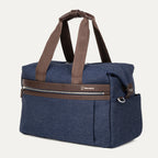 a three-quarter perspective view of the true navy travelpro platinum elite underseat tote, highlighting the textured blue fabric, brown leather trim, front zippered pocket, and side accessory pocket.