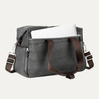 a vintage grey travelpro platinum elite underseat tote shown with a white laptop being inserted into the internal padded electronics sleeve, highlighting the bag's organization and protection for tech devices.