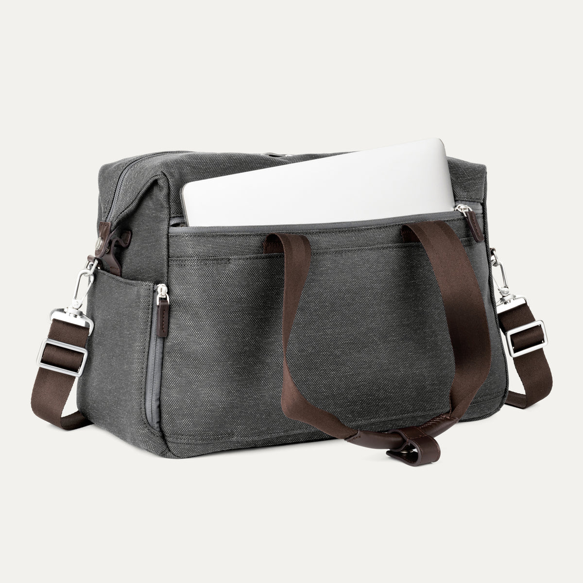 a vintage grey travelpro platinum elite underseat tote shown with a white laptop being inserted into the internal padded electronics sleeve, highlighting the bag's organization and protection for tech devices.