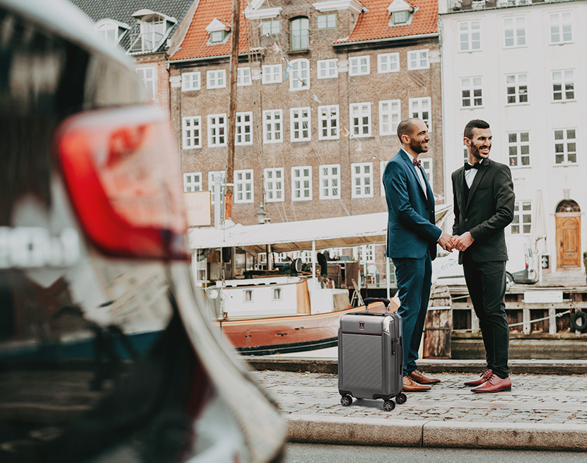 two grooms on sidewalk with luggage at their side